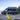 Gray Ford Transit camper van on a road with mountains and trees in the background with Vanspeed Ford Transit Capsules 148 NON EXT installed 